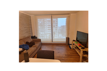 view of a living room with a sofa, entertainment center, and glass sliding doors with the shades down