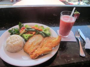 a plate with grilled chicken, vegetables, and rice with a strawberry smoothie