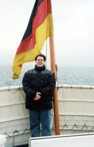 a teenager standing on a ship with the German flag in the background